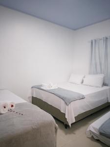 two beds in a room with white walls at Pousada Descanso Do Preguiça in Barreirinhas