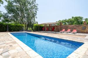 a swimming pool with blue water and red chairs at Serra de Prades in Montblanc