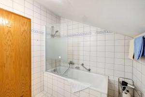 a white tiled bathroom with a bath tub at Fewo Brünnstein - Nr 60 Pool, Sauna in Oberaudorf +12 photos