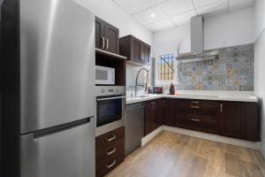 a kitchen with wooden cabinets and a stainless steel refrigerator at Villa Pastrana in Chipiona