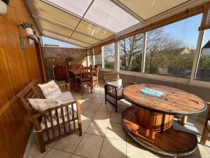 a screened in porch with a wooden table and chairs at L'escale Kénanaise in Saint-Quay-Perros