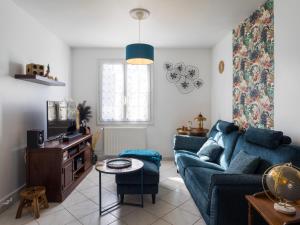 a living room with a blue couch and a tv at L'escale Kénanaise in Saint-Quay-Perros