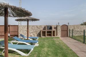 two chairs and an umbrella in a yard at Casa Carmelo 1 familas o parejas in Conil de la Frontera