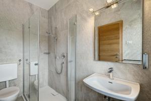 a bathroom with a sink and a glass shower at Premium App Hofer Sandra in Villabassa +25 photos