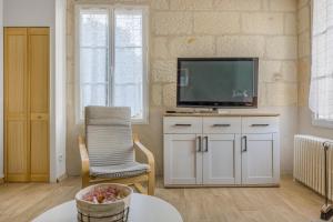 a living room with a television and a chair at Le Relax 41 in Saint-Aignan