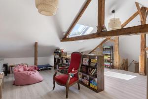 a room with a red chair and a book shelf at Gîte Bricabroc 2 adultes 2 enfants in Noyant