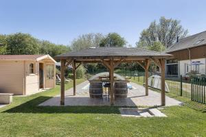 a wooden gazebo with a table in a yard at Gîte Bricabroc 2 adultes 2 enfants in Noyant