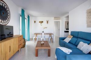 a living room with a blue couch and a table at Atico Playa Gandia in Playa de Gandia