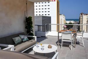 a patio with a couch and a table on a balcony at Atico Playa Gandia in Playa de Gandia