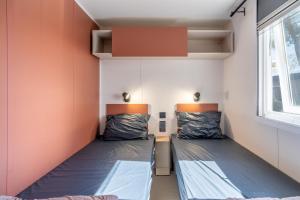 two beds in a small room with a window at Mh sympa au camping domaine la yole in Vendres +27 photos