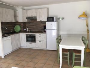 a kitchen with a table and a white refrigerator at Charmant Appartement - Bordaberry in Urrugne +4 photos