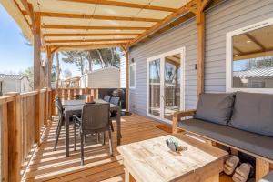 a patio with a table and a couch on a deck at Mh sympa au camping domaine la yole in Vendres