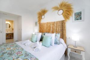 a bedroom with a white bed with blue and green pillows at Terrazas de doñana b91a in Sanlúcar de Barrameda