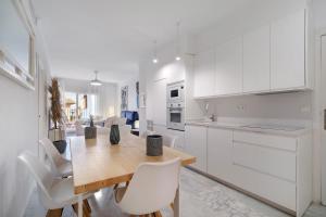 a kitchen and dining room with a wooden table and white cabinets at Terrazas de doñana b91a in Sanlúcar de Barrameda