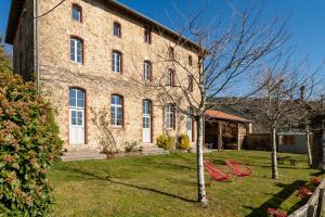 a large brick building with two red boats in the yard at Cabane Ecolodge La Chastanha in Saint-Symphorien-de-Mahun