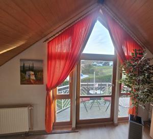 a room with a large window with red curtains at Haus Herdi-Schön in Herdwangen-Schönach