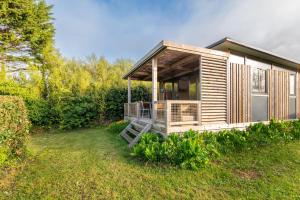 a small cabin with a porch in the grass at Chalet 35m2 - Molène in Plouhinec +12 photos