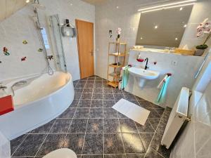 a bathroom with a tub and a sink at Haus Herdi-Schön in Herdwangen-Schönach +22 photos