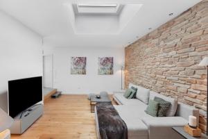 a living room with a couch and a brick wall at Hygge Home Schwarzwald in Villingen-Schwenningen