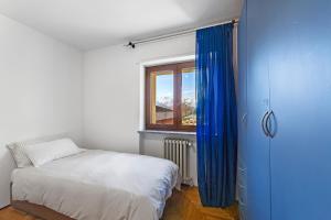a bedroom with a bed and a window with blue curtains at Alpenglow Maison Lugon in Saint-Christophe