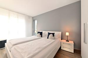 a white bedroom with a large white bed and a window at Dinkelbach Traumblick 3 C in Hengnau