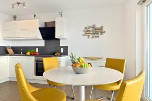 a kitchen with a white table and yellow chairs at Dinkelbach Traumblick 3 C in Hengnau
