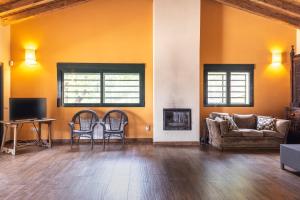a living room with orange walls and a couch and chairs at La Morada De Piedralaves in Piedralaves