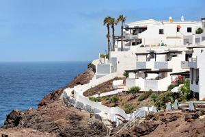 a white building on a cliff next to the ocean at El Rinconcito del Faro in Gáldar