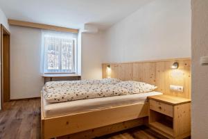 a bedroom with a wooden bed and a window at Thusnelda Apartment A in Siusi