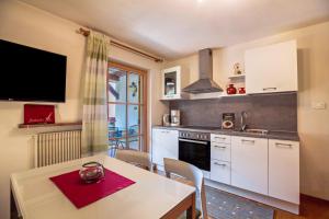 a kitchen with white cabinets and a table with a dining room at Appartements Gabrielli Marie in Trodena