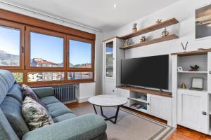 a living room with a blue couch and a flat screen tv at Comarca del Sella in Arriondas