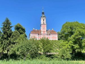 a large pink building with a tower on top of trees at Guck zum Bodensee in Uhldingen-Mühlhofen