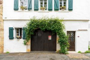 a white building with a black door and green ivy at Studio Tamburine Xaharra in Ainhoa