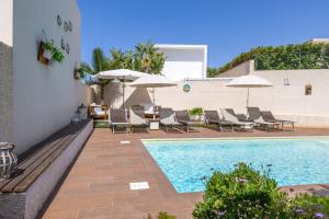 a pool with chairs and umbrellas next to a building at Villa Heraia con piscina in Marina di Ragusa