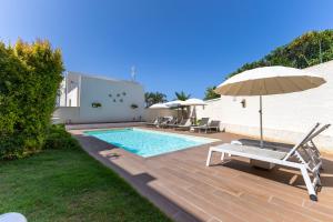 a swimming pool with an umbrella and a chair and an umbrella at Villa Heraia con piscina in Marina di Ragusa