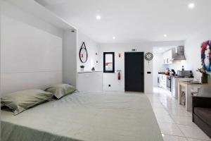 a white room with a bed and a kitchen at Mi Casa Es Su Casa Nº1 in Albufeira