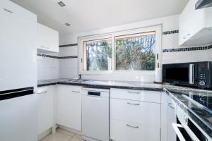 a kitchen with white cabinets and a window at Courtille sur Mer - port de Frejus in Fréjus