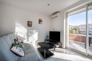 a living room with a couch and a television and a balcony at Courtille sur Mer - port de Frejus in Fréjus