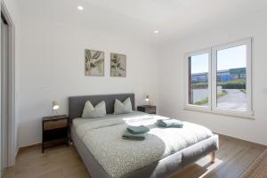 a white bedroom with a bed and two windows at Drop In Beach Apartments in Lourinhã +66 photos