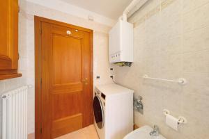 a small bathroom with a washing machine and a wooden door at Appartamento Al Pelmo a Vinigo in Vinigo +20 photos