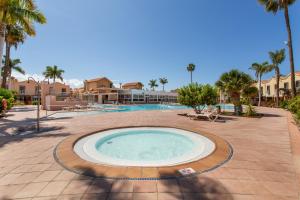 a large swimming pool in a courtyard with palm trees at Maspalomas Green Oasis in San Bartolomé