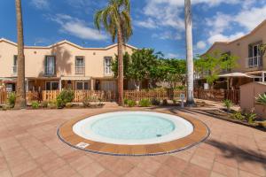 a swimming pool in a courtyard with palm trees at Maspalomas Green Oasis in San Bartolomé