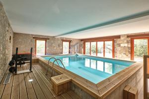 a large indoor pool with a wooden deck and a large swimming pool at Maison Dans Ancienne Forge in Noyarey