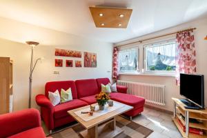 a living room with a red couch and a tv at Brujosenhof in Oppenau