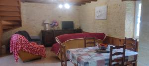 a living room with a table and chairs and a television at Terre De Pierres - Gite Améthyste in Saint-Geniès