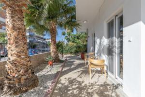 a patio with a table and chairs next to a palm tree at Luxsuites in Chania