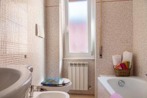 a bathroom with a toilet and a tub and a window at Mariva in Germignaga