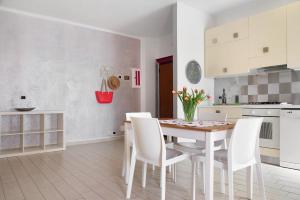 a white kitchen with a table and white chairs at Mariva in Germignaga +20 photos