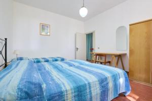 a bedroom with a blue and white bed and a desk at Mare Etrusco 5 in Populonia