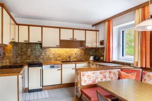 a kitchen with white cabinets and a table with chairs at Ferienwohnung Pfeffer in Leogang